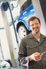 Portrait confident mechanic in auto repair shop - obrazy, fototapety, plakaty