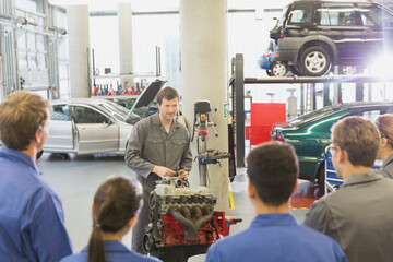 Mechanic explaining car engine to students in auto repair shop - obrazy, fototapety, plakaty