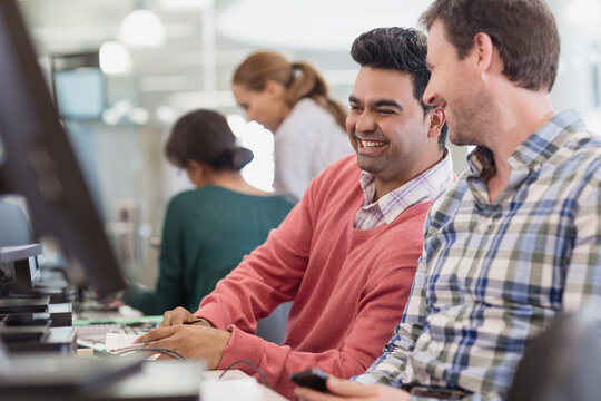 Men laughing at computer in adult education classroom