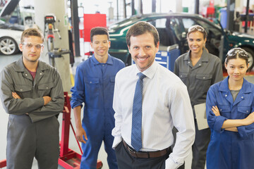 Portrait confident businessman and mechanics in auto repair shop