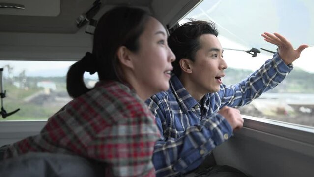 캠핑카 창문을 열고 밖을 내다보며 즐거워하는 부부