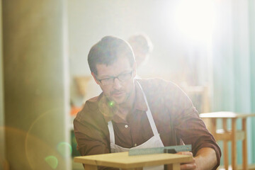 Focused carpenter measuring wood in workshop