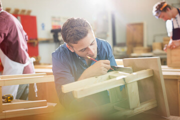 Carpenter measuring and marking wood in workshop