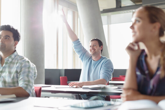 Eager man raising hand in adult education classroom
