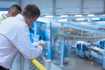 Workers leaning on railing overlooking factory