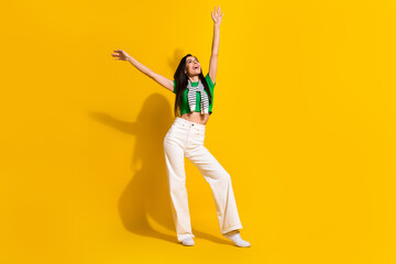 Obraz premium Full body photo of stunning overjoyed lady raise hands have good mood clothes advert empty space isolated on yellow color background