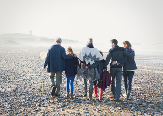 Multi-generation family walking in a row on beach