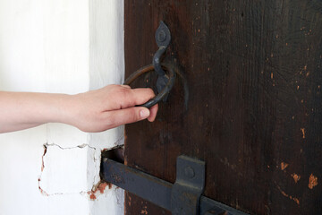 Woman's hand trying to open an antique wooden door