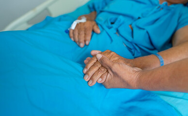 old asian man lying on bed,female hand's holds father hand,touch,love,sad for support,help,care in...