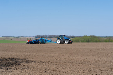 The tractor drives across the field and cultivates the land. Agricultural vehicle works in...