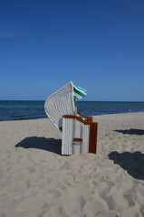 Emtpy beach chair in the sand, sea background, blue sky