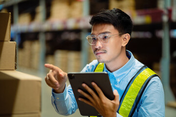 Young warehouse worker counting items on a laptop computer to check stock in stock before shipping to customer. Logistic business concept.