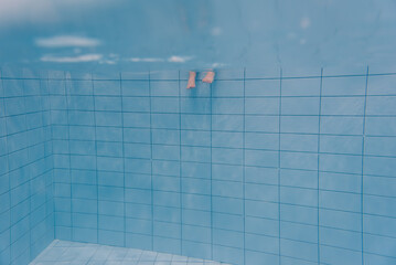 Feet of people moving under the water in the pool. Children legs. Summer. Funny underwater legs in...