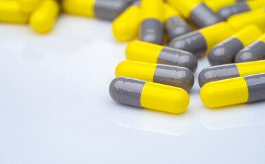 Closeup yellow and gray capsule pills on white background. Prescription drugs. Pharmaceutical industry. Health and medical care concept. Pharmacy products. Capsule pills production manufacturing.