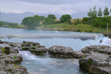 river among rocks and forest, picturesque scenery, steam over waterfall