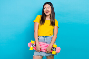 Photo of cheerful nice person hold skateboard look empty space isolated on blue color background © deagreez