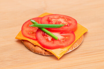 Crispy Cracker Sandwich with Tomato, Cheese and Green Onions on Cutting Board. Easy Breakfast. Diet Food. Quick and Healthy Sandwiches. Crispbread with Tasty Filling. Healthy Dietary Snack