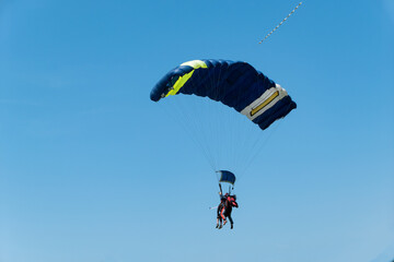 Pará-quedas no céu. Paraquedistas voando num pára-quedas no céu azul