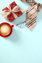 Happy Father's Day concept. Top view, flat lay vintage gift box with ribbon bow, coffee cup, glasses, tie on blue table.