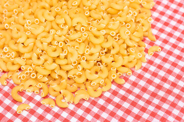 Scattered Uncooked Chifferi Rigati Pasta on Red Checkered Towel. Fat and Unhealthy Food. A Heap of Classic Dry Macaroni. Italian Culture and Cuisine. Raw Pasta