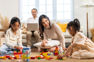 Naklejka premium Portrait of enjoy happy love asian family father and mother with little asian girl smiling activity learn and skill brain training play with toy build wooden blocks board education game at home