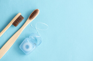 Bamboo toothbrushes and dental floss on a blue background. Hygiene and dental care concept
