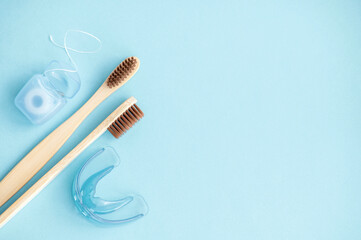 Bamboo toothbrushes, dental floss, mouthguards on a blue background. View from above. Flat lay. Hygiene and dental care concept