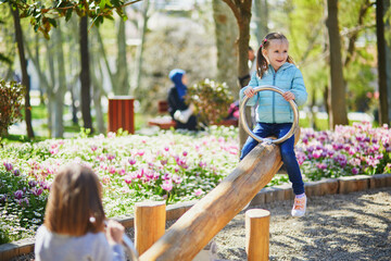 Two adorable preschooler girls having fun on seesaw in Gulhane park