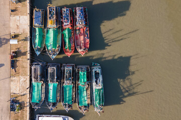 Aerial view of fishing boats moored at marina. Top view from drone of traditional motorboats in dock at phuket, Thailand. Nautical vessel transportation and fishing industry