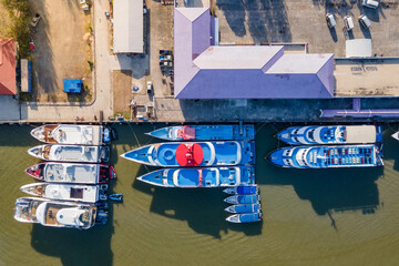 Fototapeta na wymiar Aerial view of tour boats moored at marina with port building nearby. Top view from drone of motorboats in dock at phuket, Thailand. Nautical vessel transportation business and marine tourism