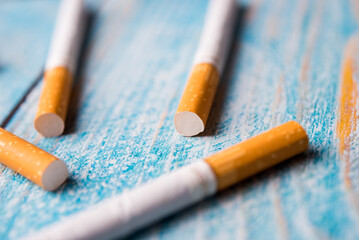 A closeup of tobacco cigarette on blue wooden background with space. Junk lifestyle.