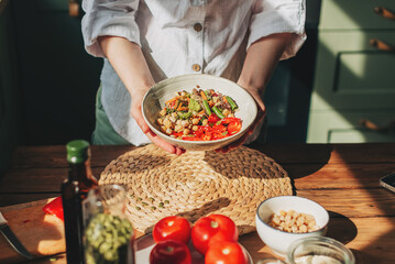 Young woman eating healthy food sitting in the beautiful interior with green flowers on the background