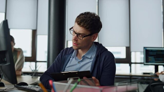 IT manager analysing online report. Thoughtful software engineer making notes