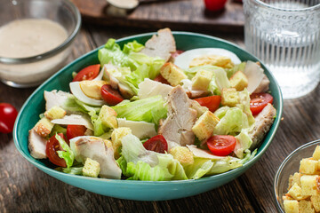 Appetizing Caesar salad in a plate on a wooden table