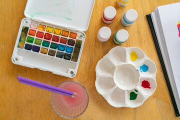 Young girl asian sitting and painting watercolour artwork to develop abilities and improve mental health at home. Female artist drawing with inspiration.