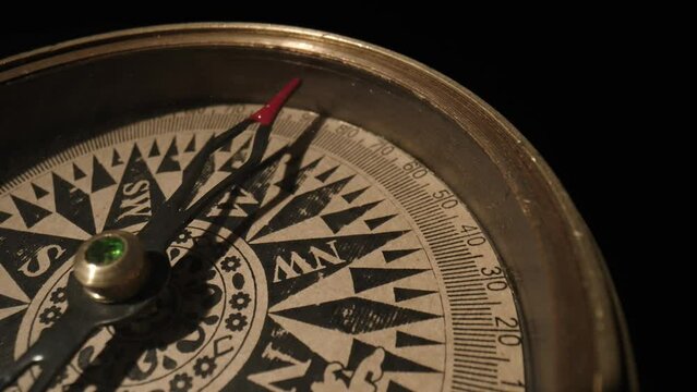Travel planning navigation concept. Vintage magnetic compass with a a rotating arrow close up on a black background.