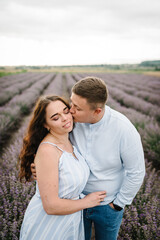 Loving couple kissing. The couple walks and enjoys the floral glade and summer nature. France, Provence. Family hugging in a purple lavender field of flowers. Honeymoon trip. Man and woman traveling.