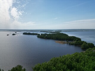 Drone view. Blue sky. Endless mirror of water. The islands are covered with greenery.
