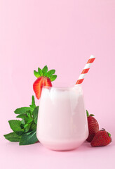 Strawberry milkshake with mint and straw on pink background