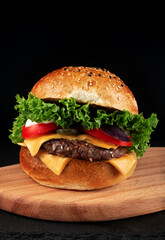 Cheese burger - American cheese burger with fresh vegetables on black background