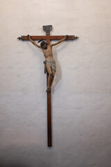 Detail of Jesus Christ nailed to the wooden cross hanging on the wall