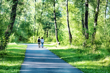 A young man and a woman walking in a park in summer.