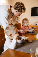 Father watching his kids eating breakfast in kitchen