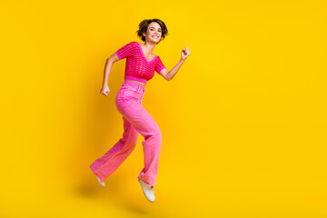 Fototapeta na wymiar Full size photo of satisfied friendly girl wear knit top pink pants running shopping empty space isolated on yellow color background