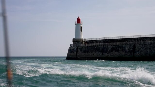 Lighthouse at the port town of Sables D'olonne in Western France with visitor railing, Wide follow shot