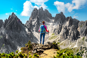 Athletic woman enjoys view on Cadini group from epic view point in the morning. Tre Cime, Dolomites, South Tirol, Italy, Europe.