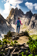 Athletic woman enjoys view on Cadini group from epic view point in the morning. Tre Cime,...