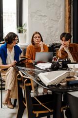 Group of architects discussing design project and using laptop while working in office