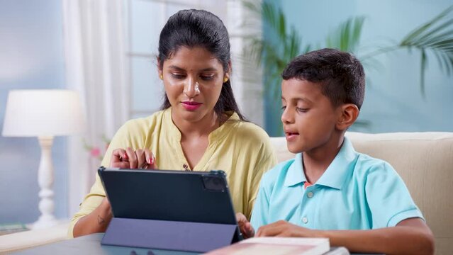 Indian mother teaching from digital tablet to his kid at home - concept of tuition, school tutor and