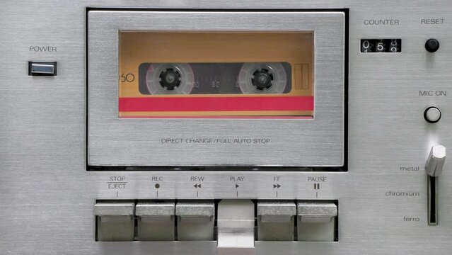Vintage silver audio cassette player playing an orange cassette tape